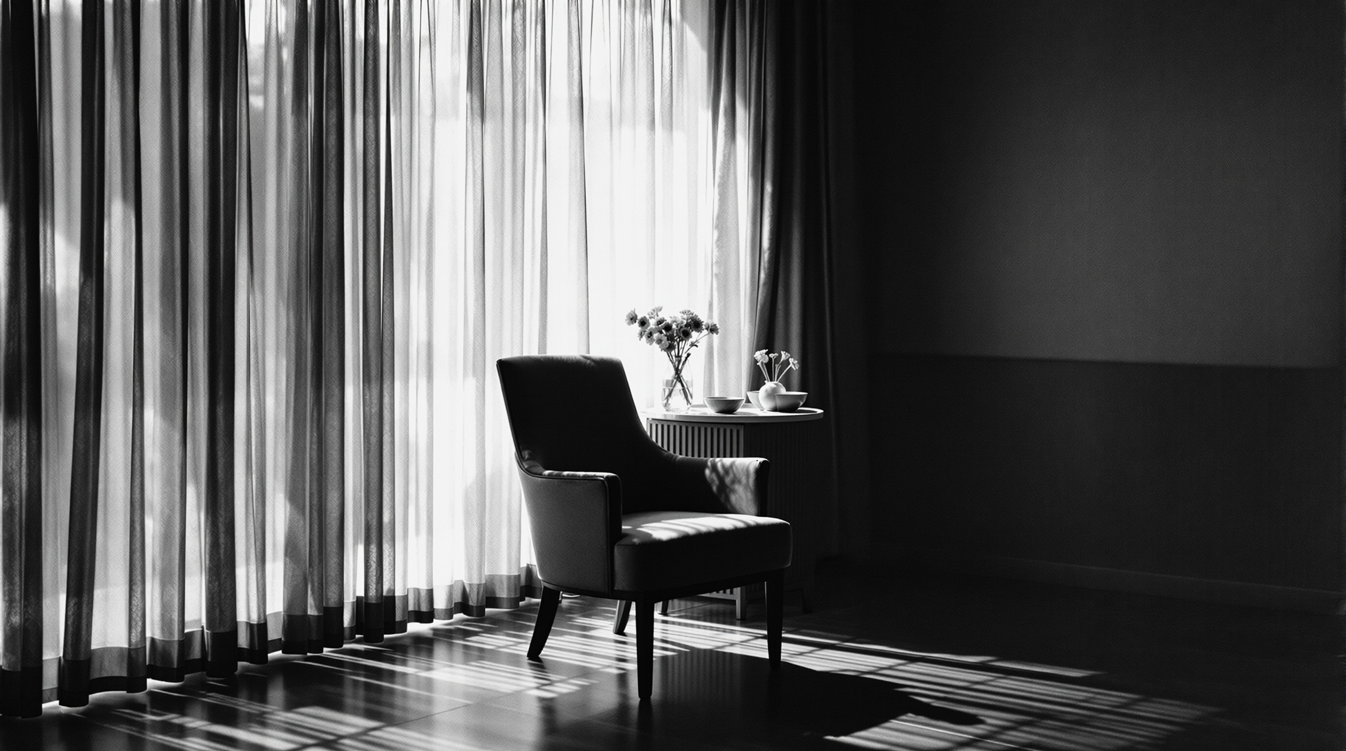 Empty armchair beside a bright window with sheer curtains and flowers on the sill