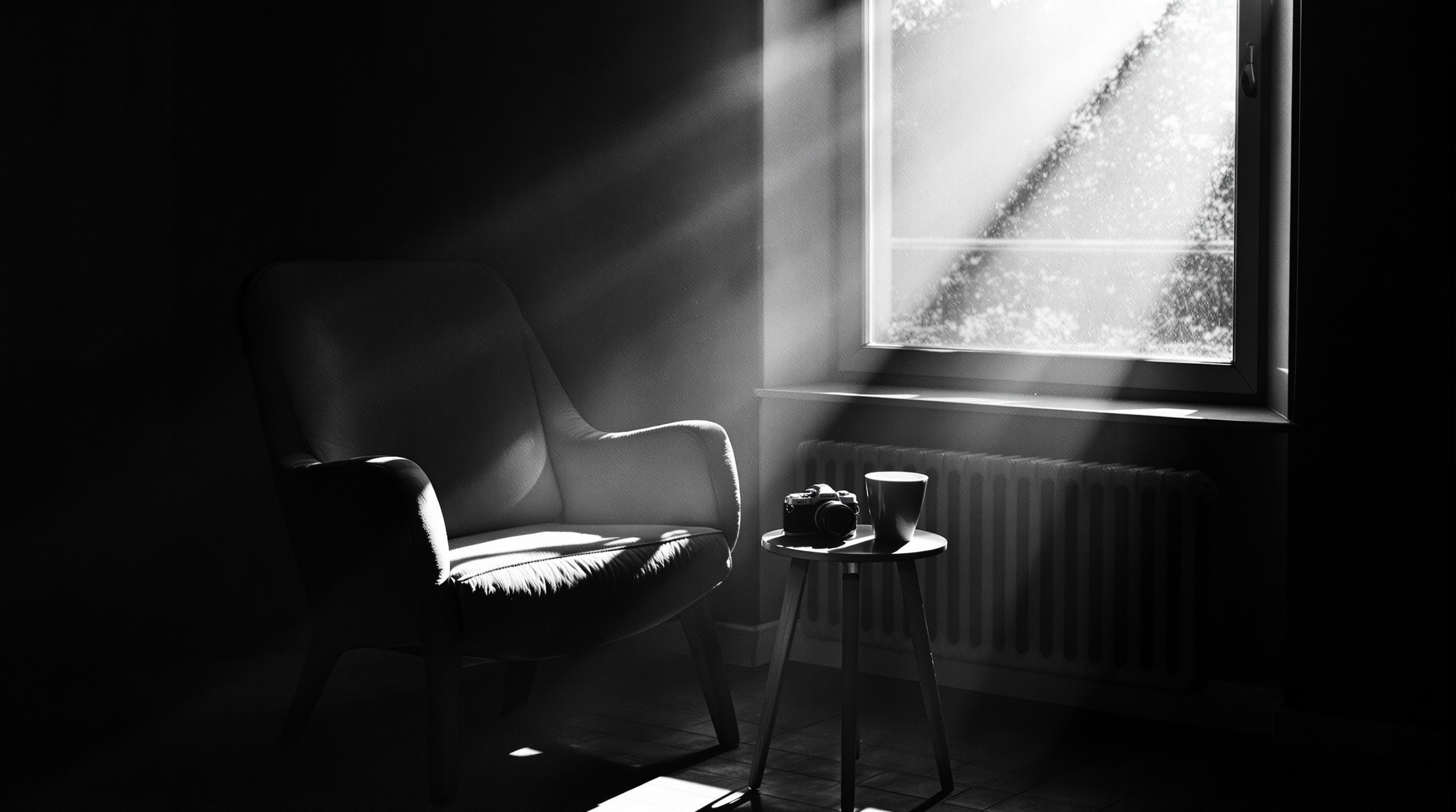 Camera and coffee cup on a table in dramatic window light beside an armchair